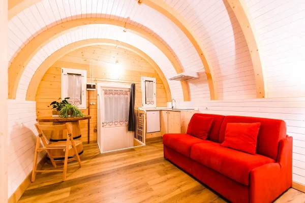Kompaktes, gemütlich eingerichtetes Tiny House mit rotem Sofa und Holzelementen.