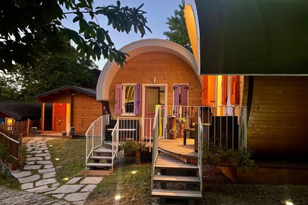 Ein charmantes Tiny House aus Holz mit beleuchtetem Weg bei Dämmerung.